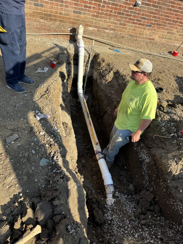 Gold's Sewer Line team member installing a sewer cleanout in a deep trench in Indianapolis