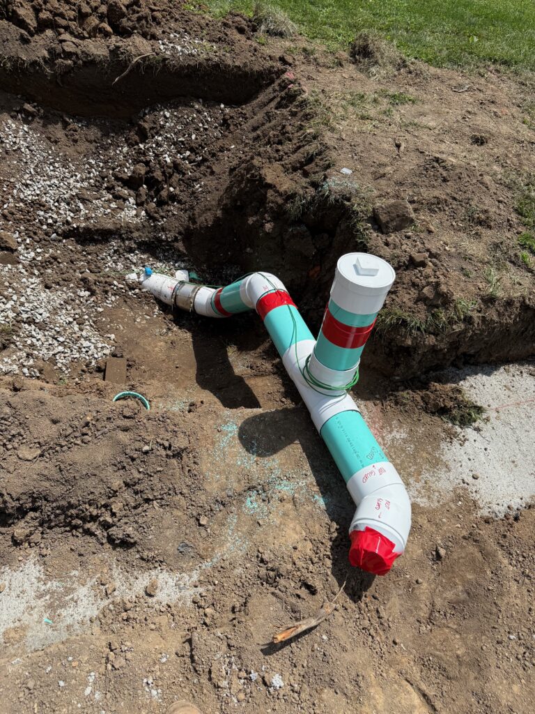 Newly installed PVC sewer pipe and cleanout with couplings in a trench