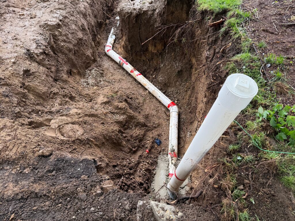 New PVC sewer line and cleanout riser installed in an excavated trench