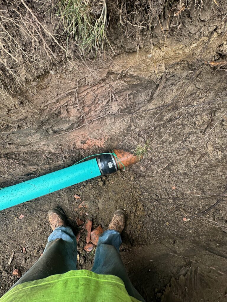 New PVC pipe joined to an old clay sewer pipe with a coupling inside the trench