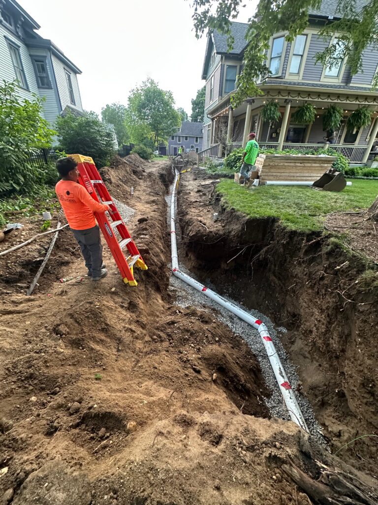 Gold's Sewer Line crew installing a new sewer line in a deep trench between two Indianapolis homes