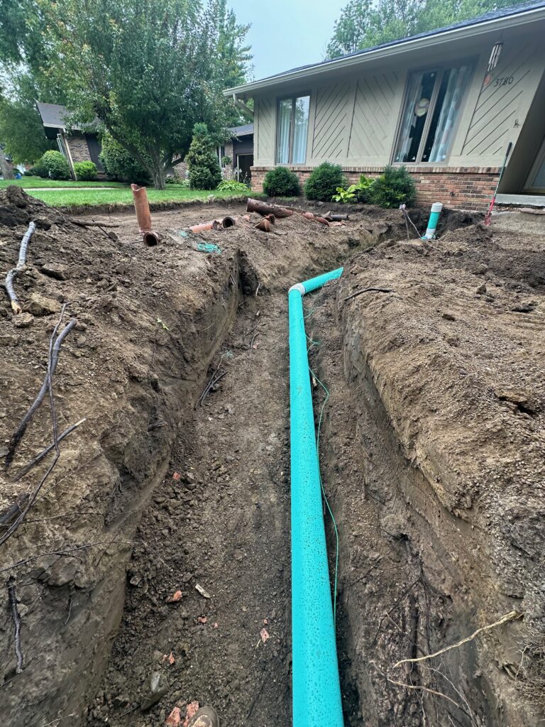 New PVC sewer line in a narrow trench in front of an Indianapolis ranch home